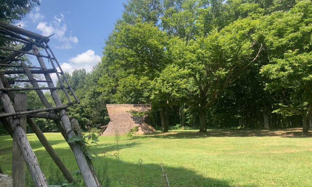 尖石遺跡の草原と復元住居、八ヶ岳の森に囲まれた風景