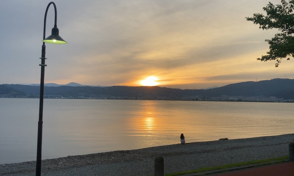 諏訪湖に沈む夕陽と湖畔のシルエット