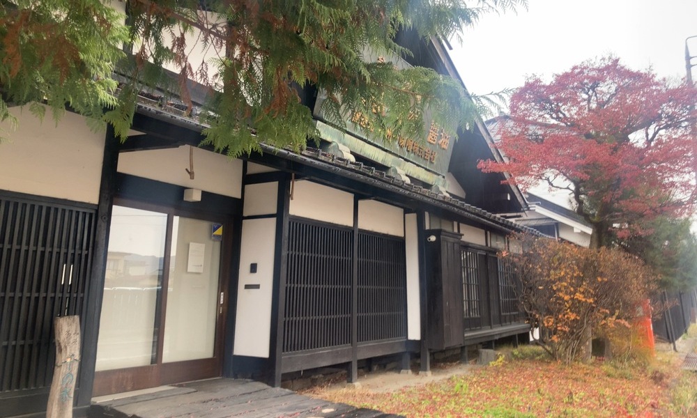 信州の味噌蔵の外観。低い屋根と厚い壁が並び、発酵のために光と風を抑えた建物が静かに佇んでいる。