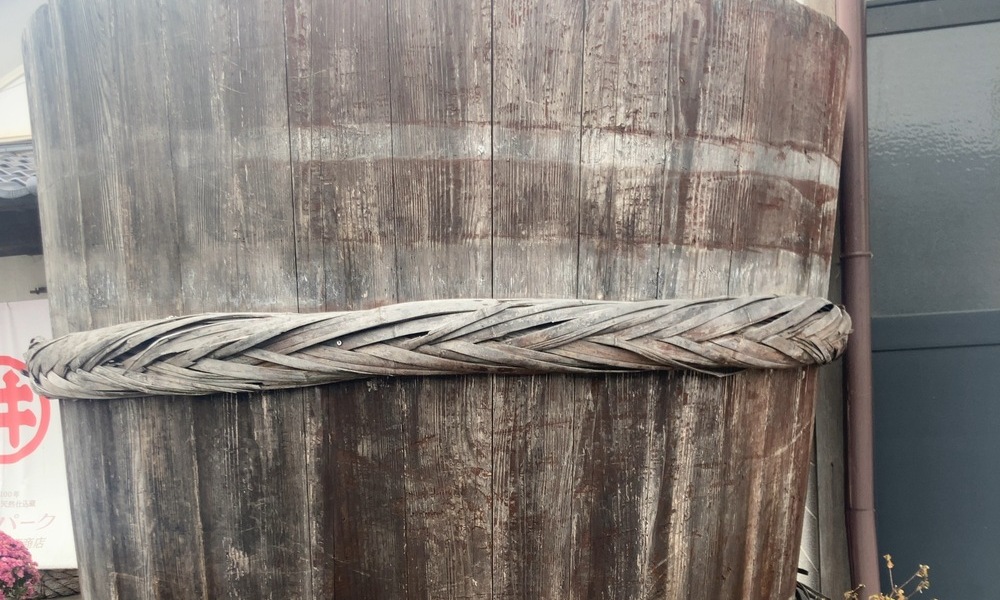 味噌蔵で使われ続けてきた木桶の外側。木の表面に経年による色むらと編まれた箍（たが）が残っている。