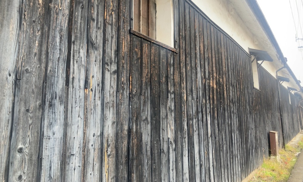 味噌蔵の外壁に使われている木板。雨風にさらされ、縦方向に経年変化した木の表情が続いている。