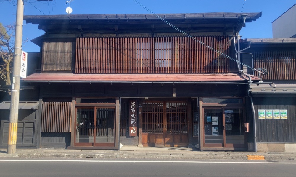 甲州街道沿いに建つ諏訪五蔵の酒蔵外観。通りに面した木造の蔵と格子戸の正面