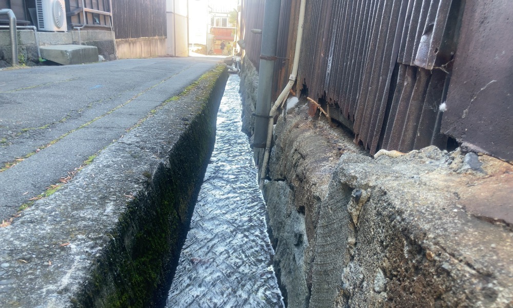 諏訪の酒蔵裏を流れる細い水路と石積みの側溝
