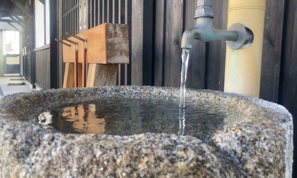 諏訪の酒蔵前に設けられた石の手水鉢と流れる仕込み水の蛇口