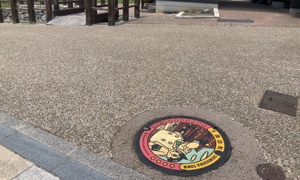 下諏訪町の秋宮近くに設置された、鉄腕アトムとお茶の水博士のデザインマンホール。