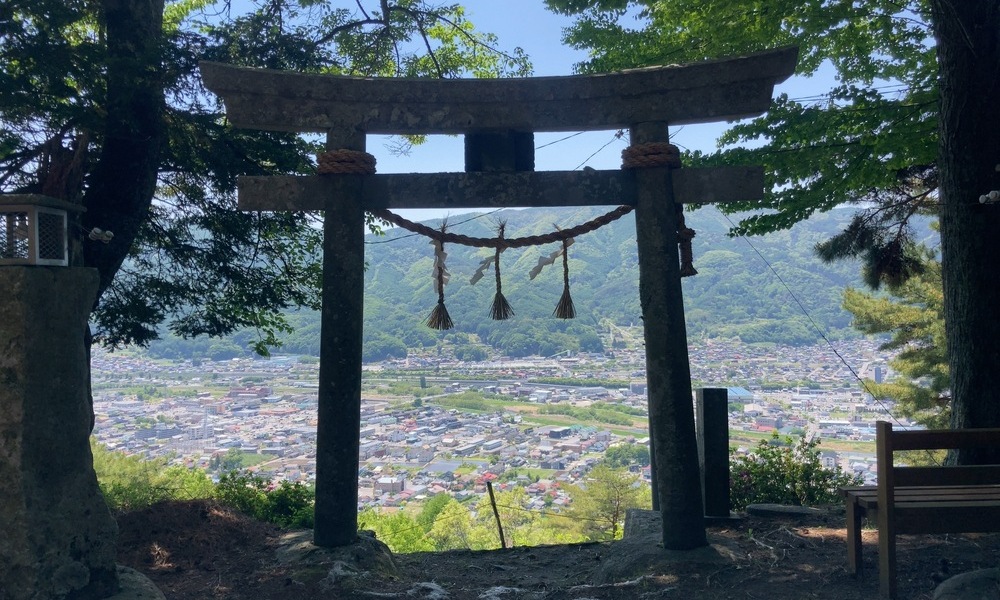 上原城跡の鳥居越しに広がる諏訪の町並み。見張りと祈りが重なる場所から、山と人の距離感を見下ろす。
