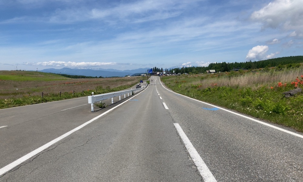 走る視点でまっすぐ先へ伸びる高原の道